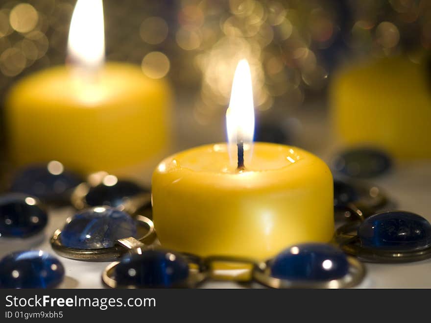 Yellow candle burns with  candles behind it.