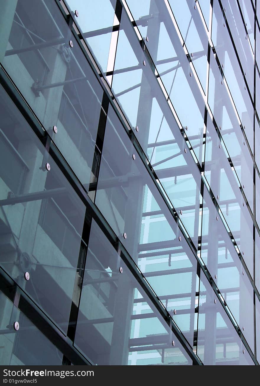 Glass construction with reflections. Blue light grey glass changing color from the sun. Concrete construction is seen behind the glass. Glass construction with reflections. Blue light grey glass changing color from the sun. Concrete construction is seen behind the glass.