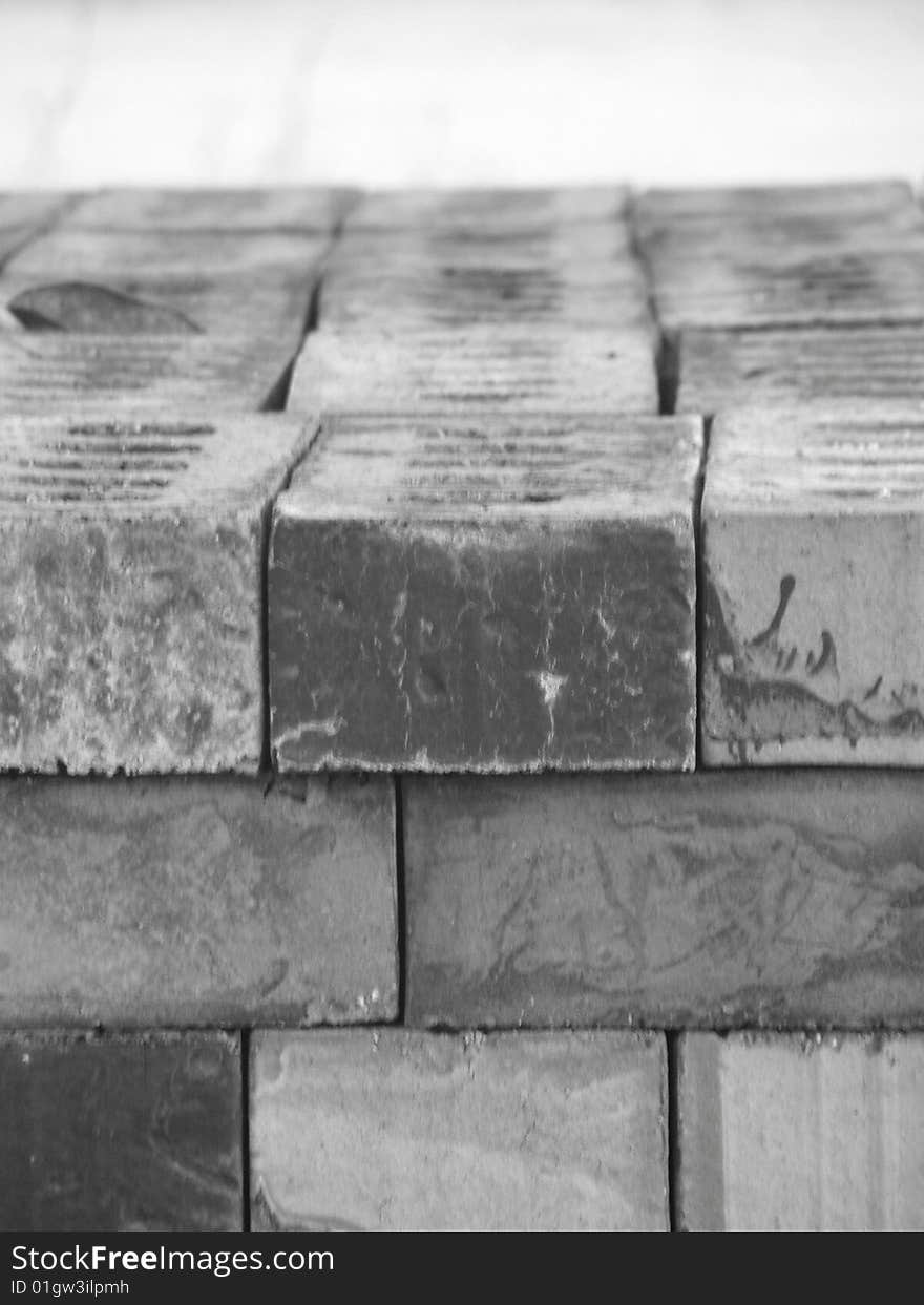 An up close black and white shot of bricks stacked up neatly on top of each . on the top you can see 4 bricks lying on there backs going length ways,  on the side you can see their sides as they are stacked on top of each other some are showing their sides others are showing their ends. An up close black and white shot of bricks stacked up neatly on top of each . on the top you can see 4 bricks lying on there backs going length ways,  on the side you can see their sides as they are stacked on top of each other some are showing their sides others are showing their ends