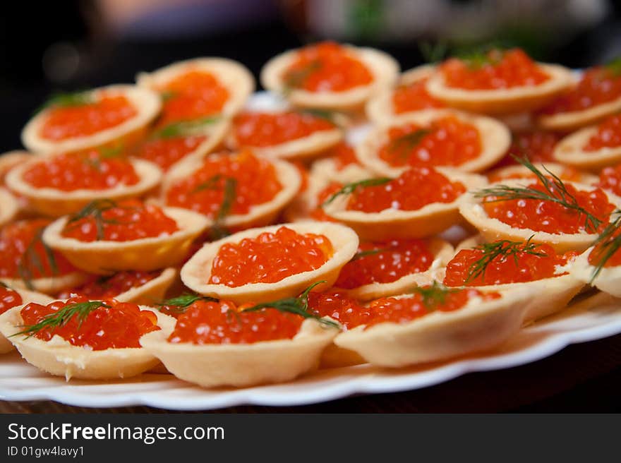 Tartlets with red caviar on a white dish