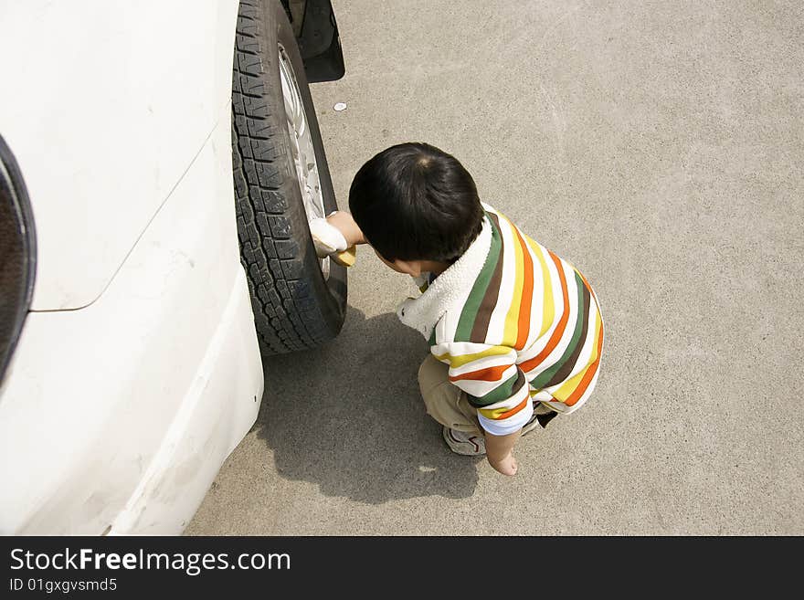 a picture of a little chinese boy washing car hard and happily