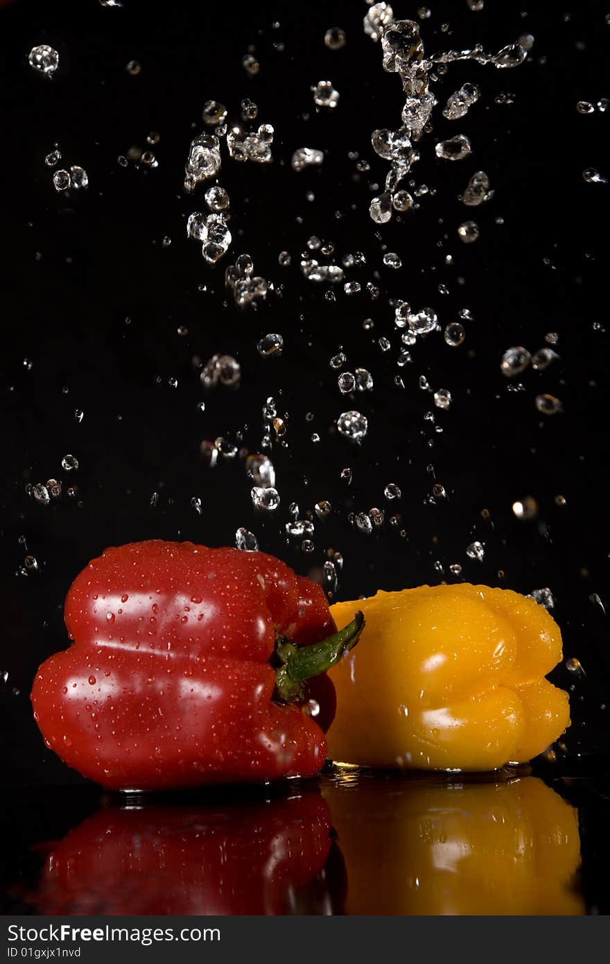 Fresh peppers and water splashes, isolated on black background