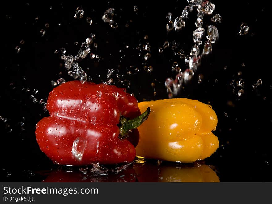 Bright peppers and water splashes, isolated on black background