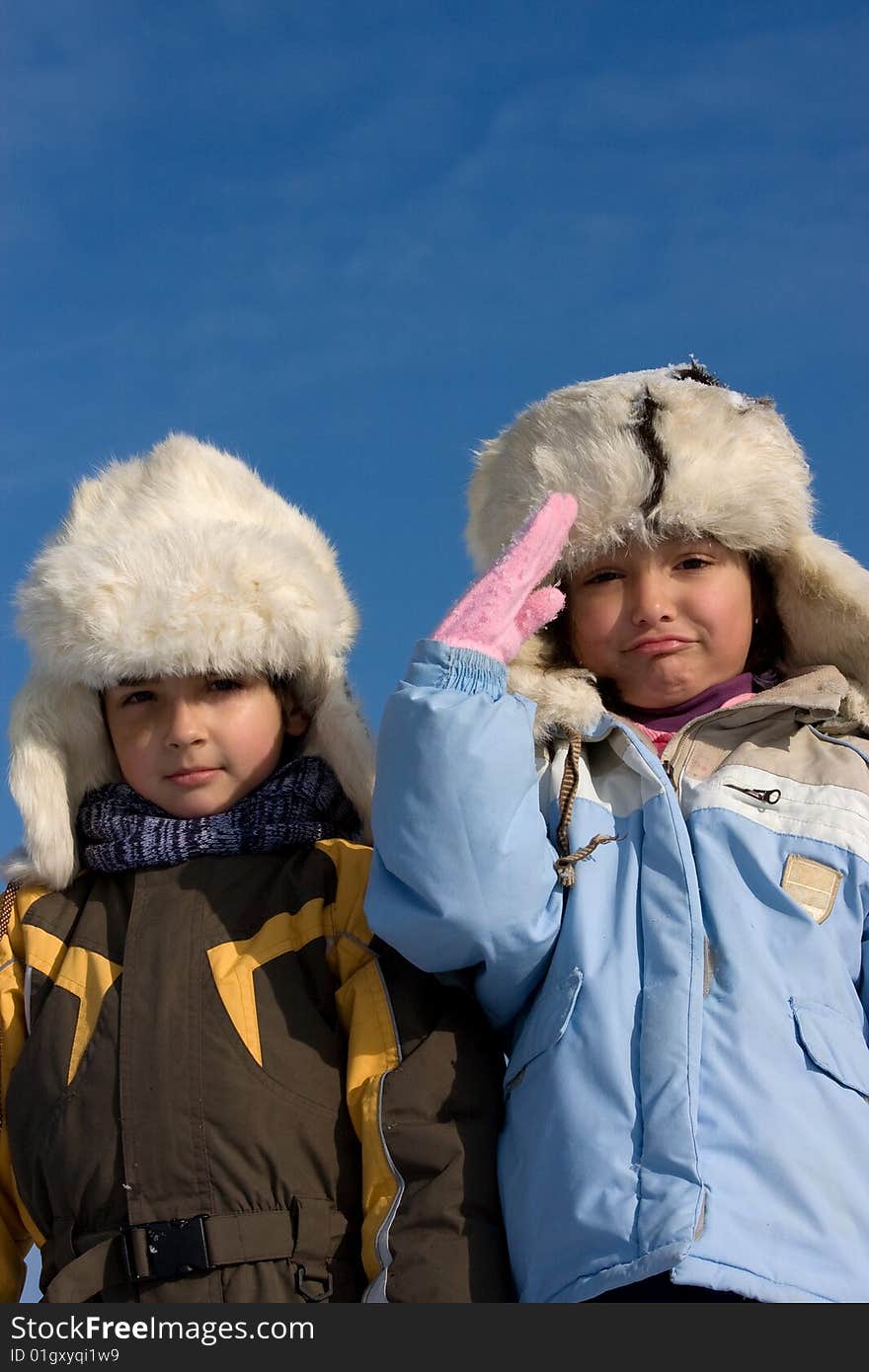 Cute girl and boy in the fur-cap in winter