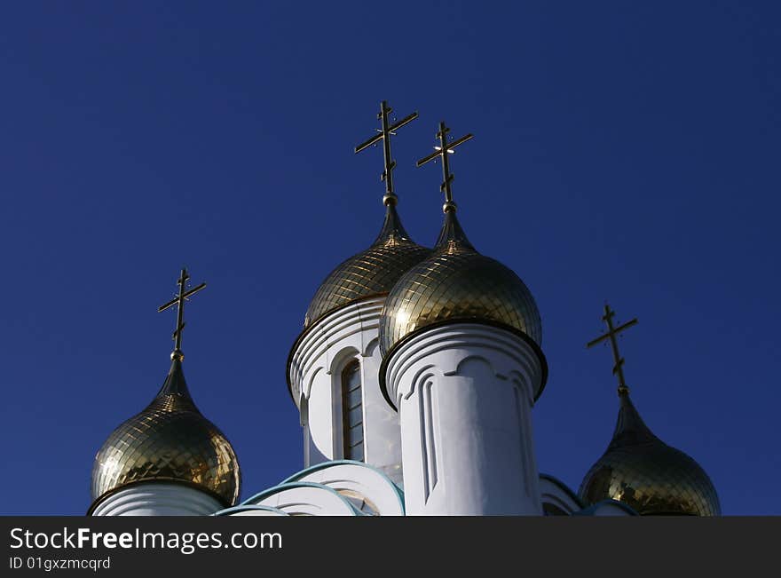 Gold cupola with the crosses over big blue sky