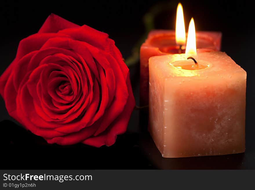 Red rose and candles over black background