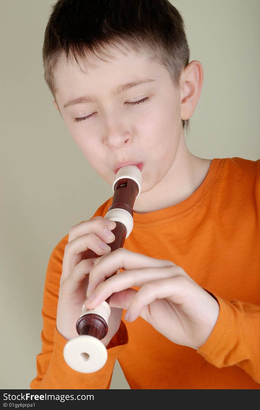 Boy in a bright T-shirt playing the flute. Boy in a bright T-shirt playing the flute