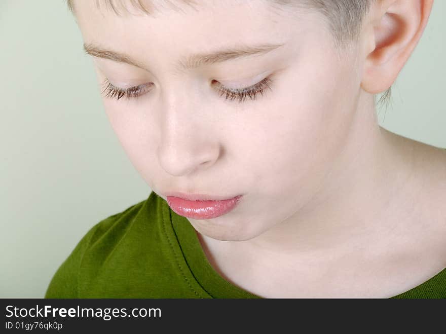 Portrait of resentful boy on a green background