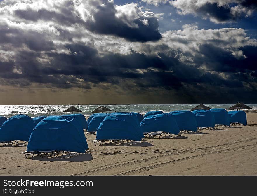 Blue Beach Shelters and Umbrellas on a beach on a cloudy day. Blue Beach Shelters and Umbrellas on a beach on a cloudy day