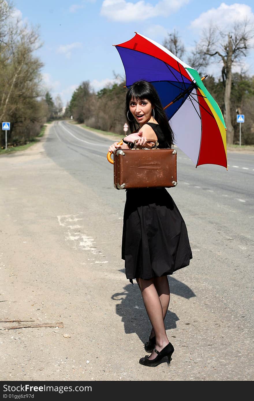 Girl with vintage suitcase and umbrella outdoors