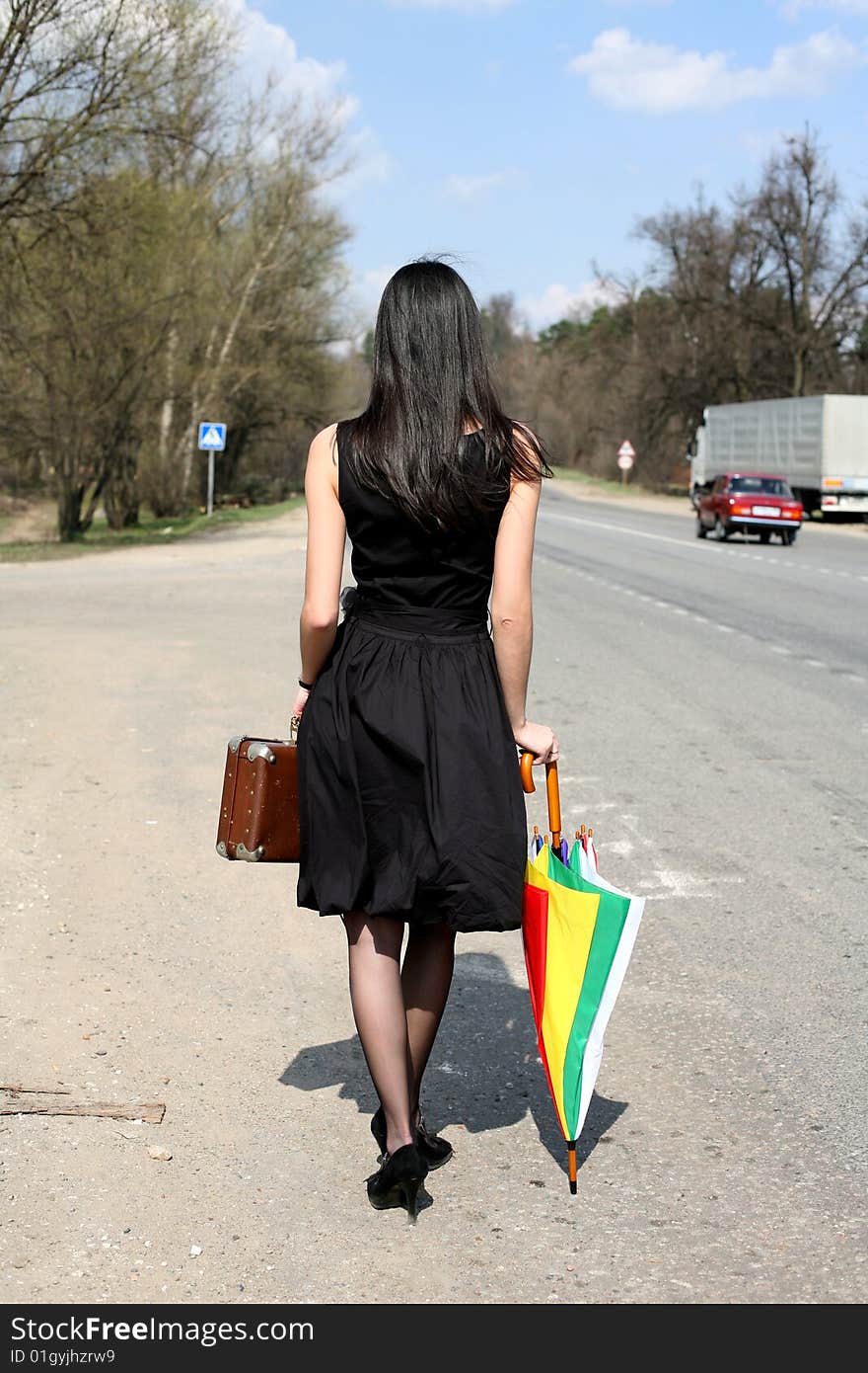 Girl with vintage suitcase and umbrella outdoors