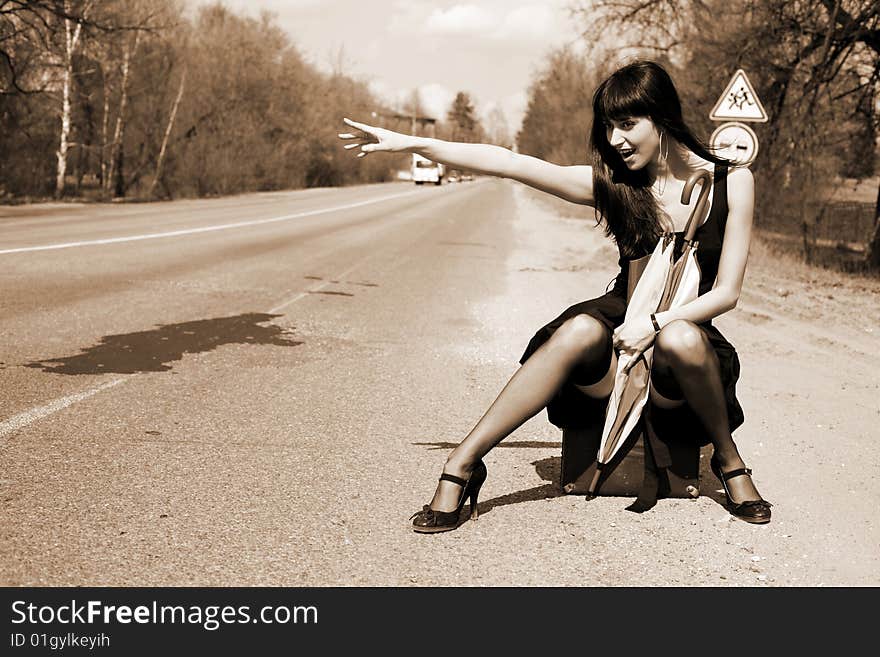 Girl in the road sit atop vintage suitcase with umbrella. Girl in the road sit atop vintage suitcase with umbrella