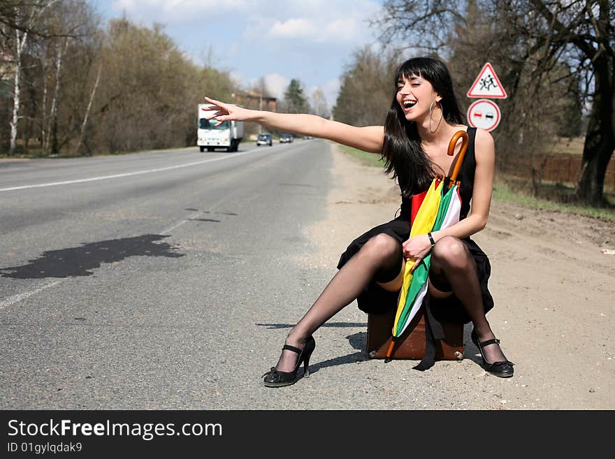 Girl in the road sit atop vintage suitcase with umbrella. Girl in the road sit atop vintage suitcase with umbrella