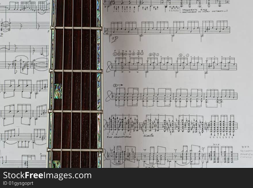 Guitar neck on sheet music. Guitar neck on sheet music