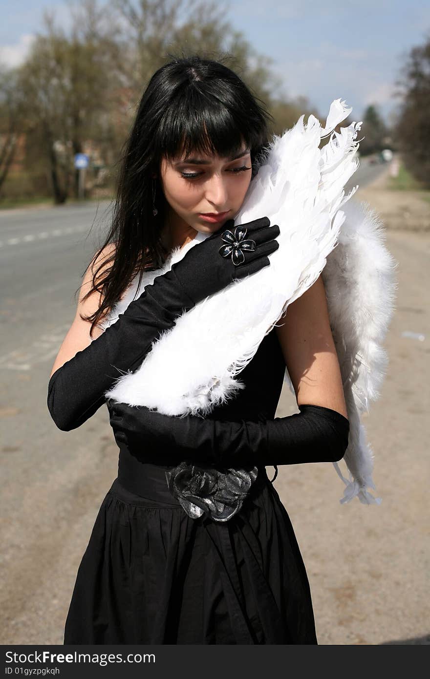 Black angel with white broken wing outdoors. Black angel with white broken wing outdoors