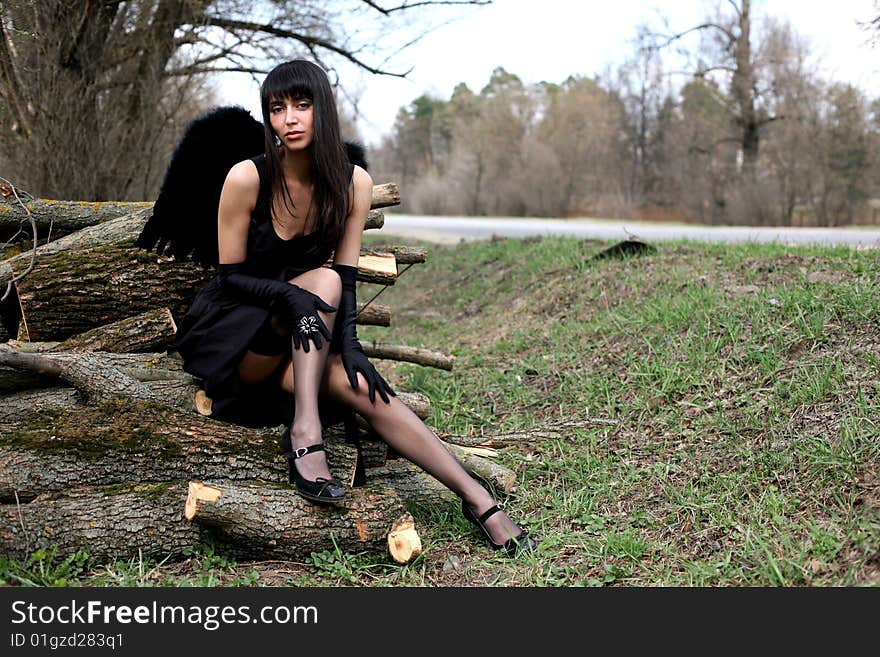 Lovely black angel outdoors in black dress