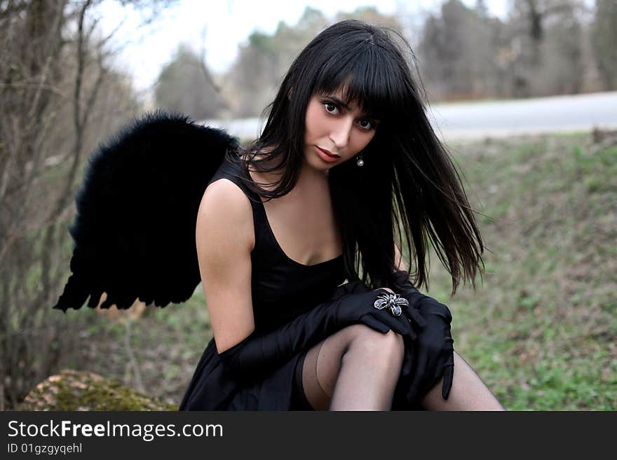 Sitting lovely black angel outdoors