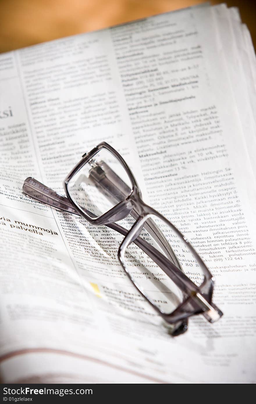 Eyeglasses and newspaper on the table.