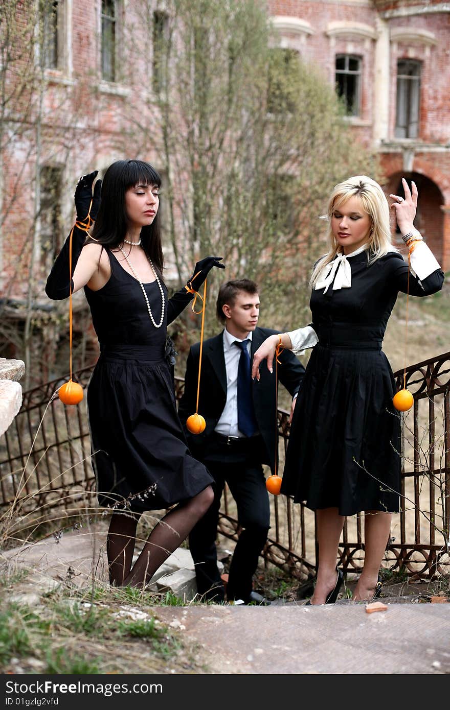 Two girls with oranges and man beside old house with. Two girls with oranges and man beside old house with