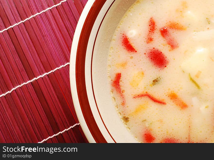 Plate with soup on a red bamboo mat