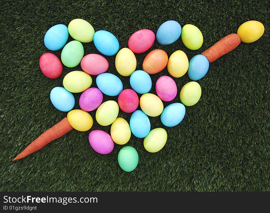 Colorful easter egg heart with carrot arrow on the green grass. Colorful easter egg heart with carrot arrow on the green grass