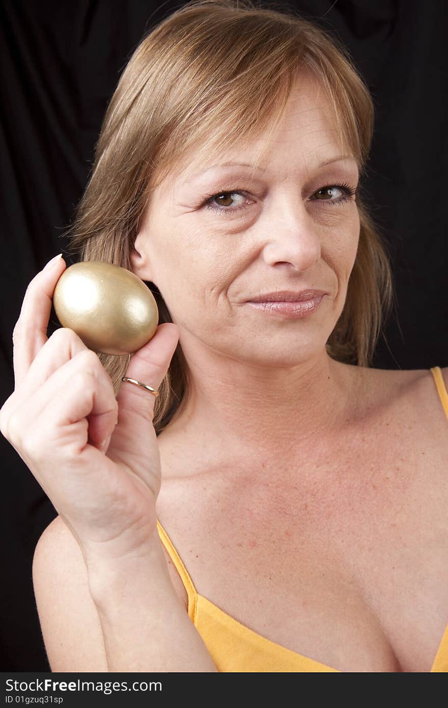 Mature woman secure in her investments symbolized by golden egg. Mature woman secure in her investments symbolized by golden egg