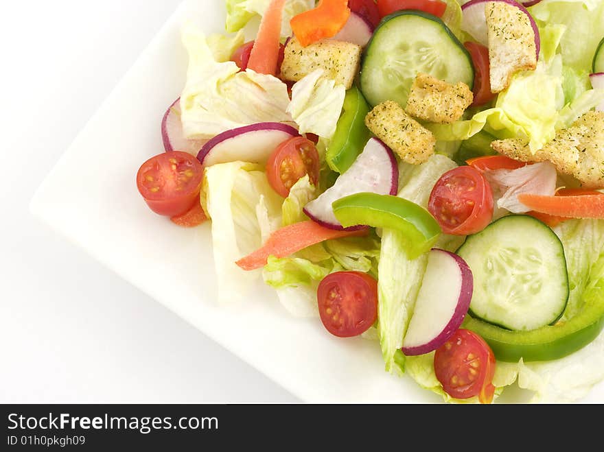 A colorful fresh garden salad in a white square bowl with white background  copy space