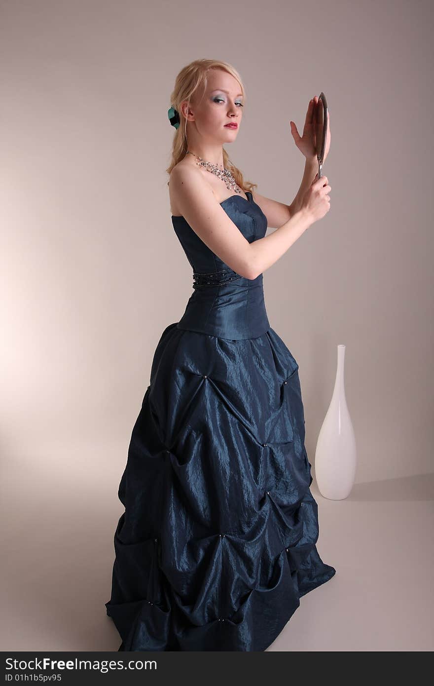 Beautiful young woman wearing a blue prom dress and silver mirror. Beautiful young woman wearing a blue prom dress and silver mirror