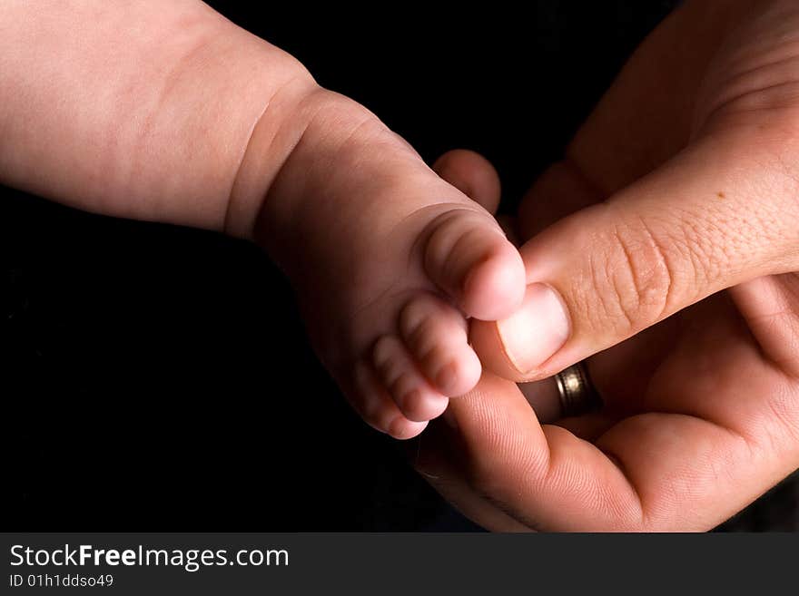 Baby's foot with dads big hand tickling it softly. Baby's foot with dads big hand tickling it softly.