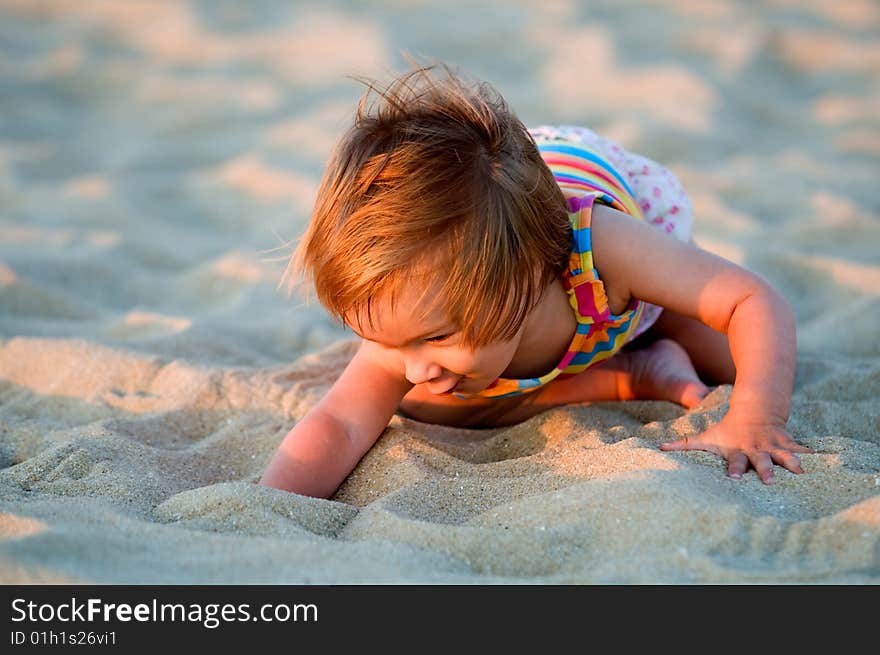 A baby-girl playing with sand on a beach. A baby-girl playing with sand on a beach