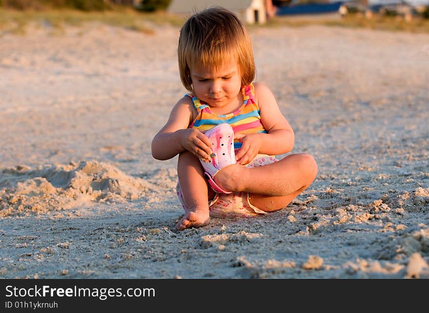 A baby-girl sitting on a beach down-under with one shoe missing. A baby-girl sitting on a beach down-under with one shoe missing