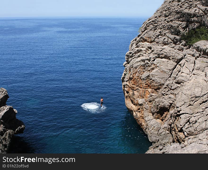 Man jumping to the ocean from the mountain