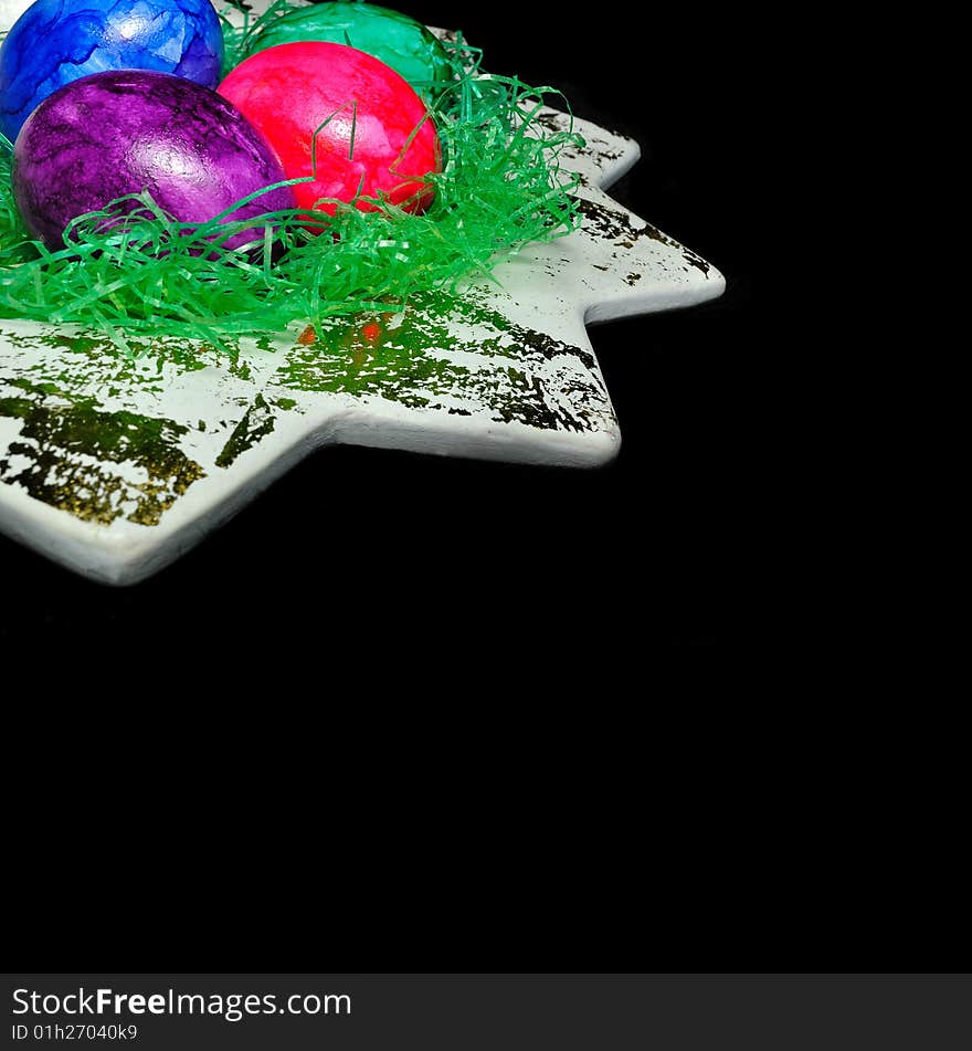 Colorful Easter eggs in a dish on the black background