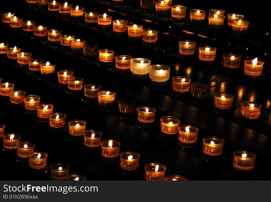 Candle lights arranged in rows, on the black background