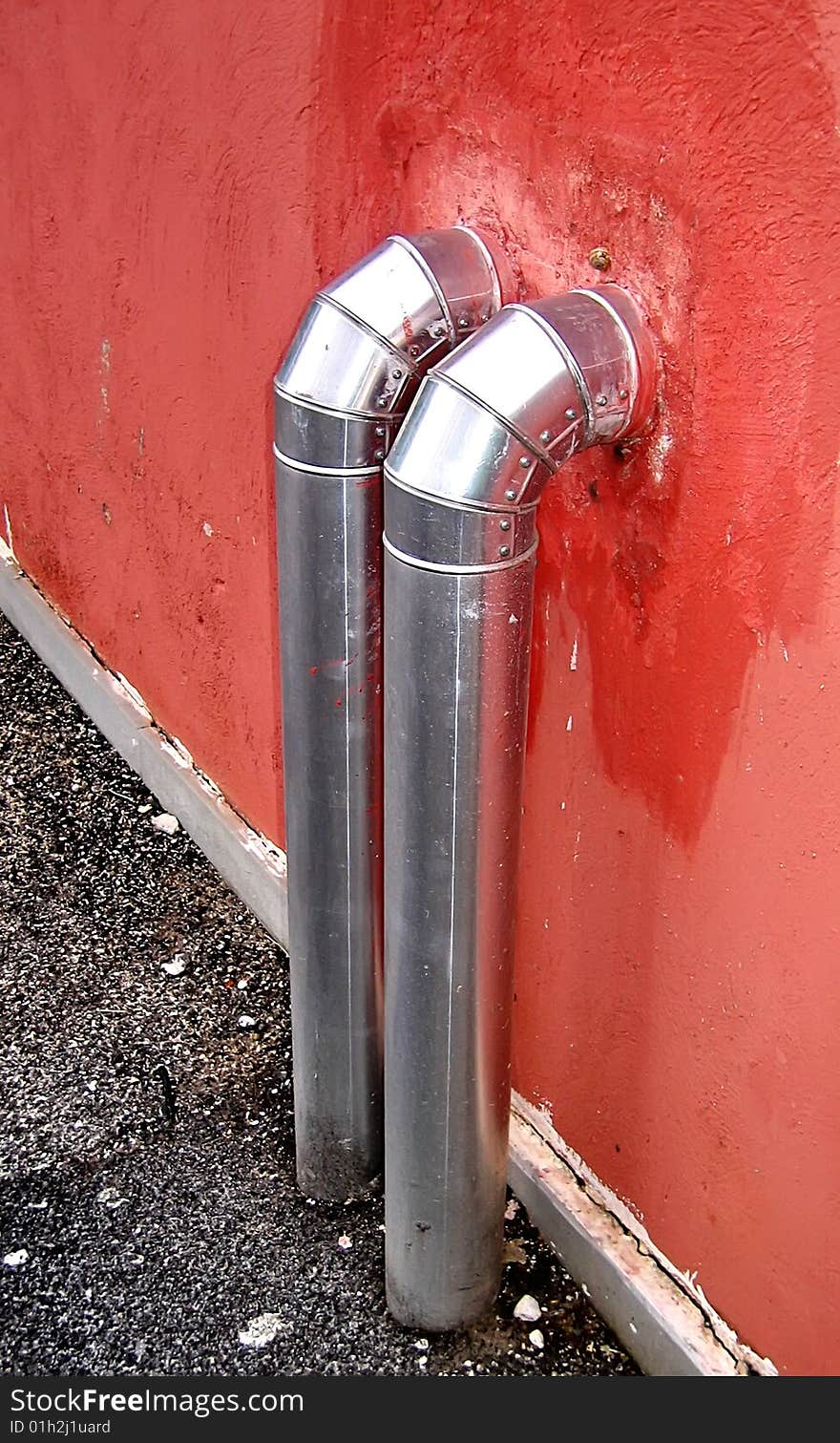 Two steel pipes entering into a red wall