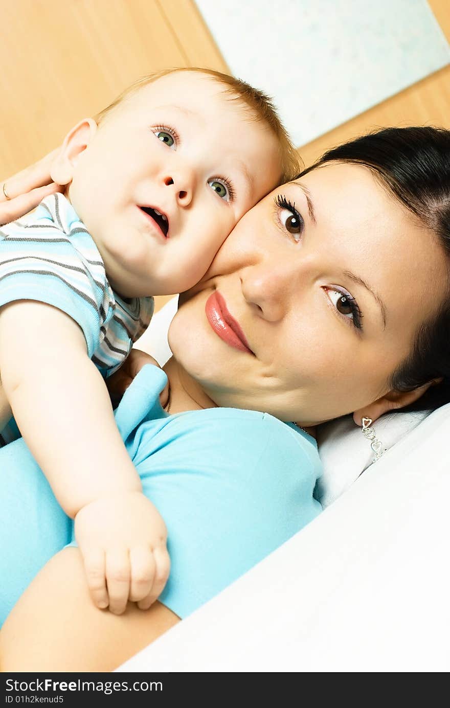 Young brunette mother and her ten months old baby on the bed. Young brunette mother and her ten months old baby on the bed