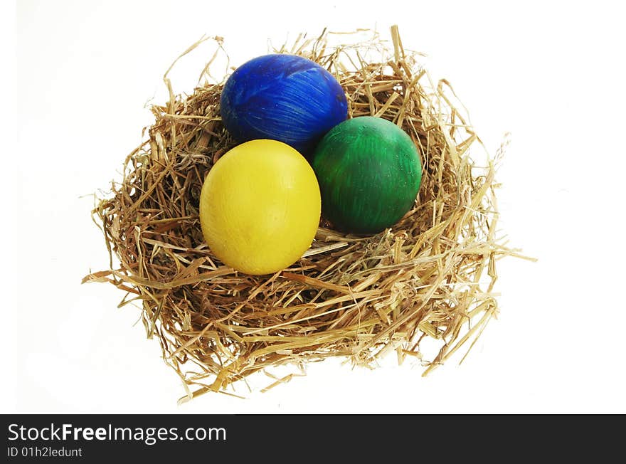 Painted eggs in a straw nest isolated on white