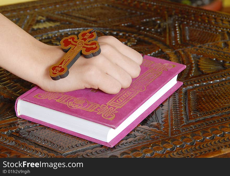 Hand on red Bible with wooden cross. Hand on red Bible with wooden cross