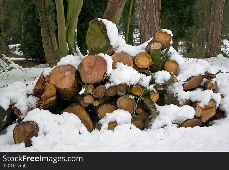 A pile of sawn logs covered in a blanket of fresh snow. A pile of sawn logs covered in a blanket of fresh snow