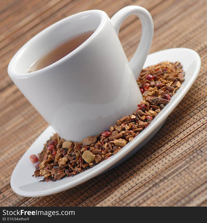 Closeup photo of a cup of spice tea on a wooden mat, with loose leaves and spices on the plate next to cup. Closeup photo of a cup of spice tea on a wooden mat, with loose leaves and spices on the plate next to cup.