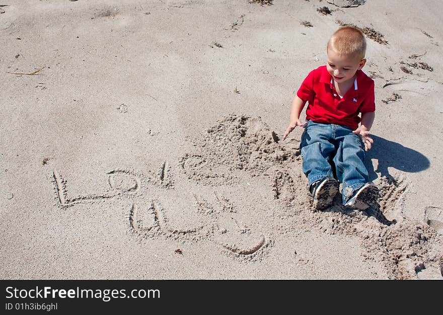 Young Boy writing in sand.