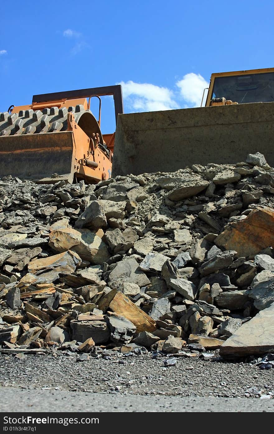 A pair of large machinery working on a empty lot moving rock around. A pair of large machinery working on a empty lot moving rock around