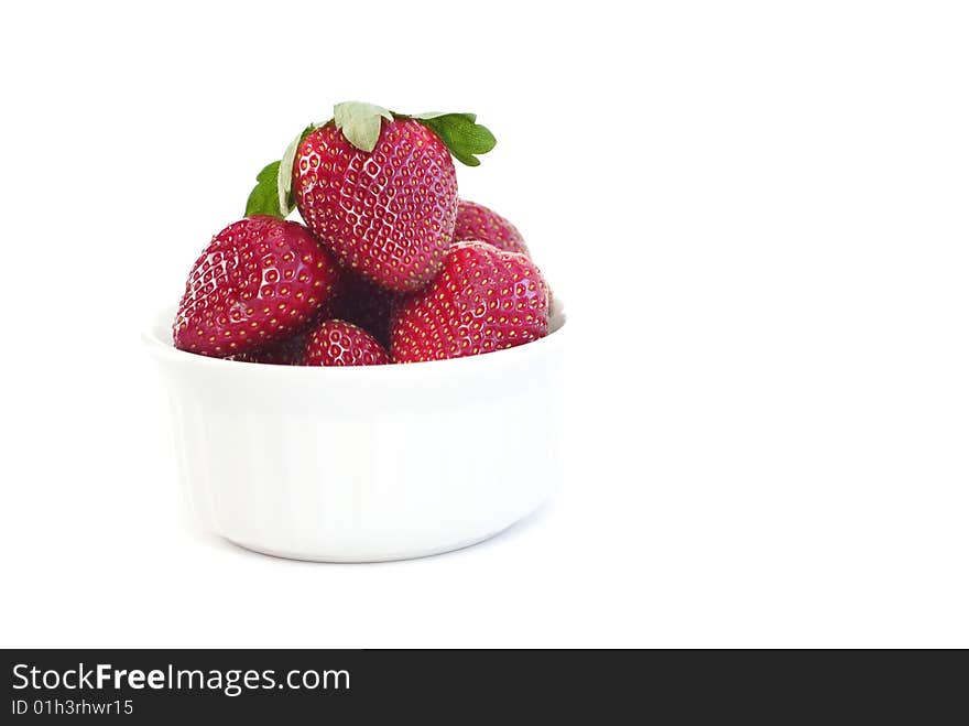 A small white bowl full of fresh whole strawberries isolated on white background with copy space. A small white bowl full of fresh whole strawberries isolated on white background with copy space