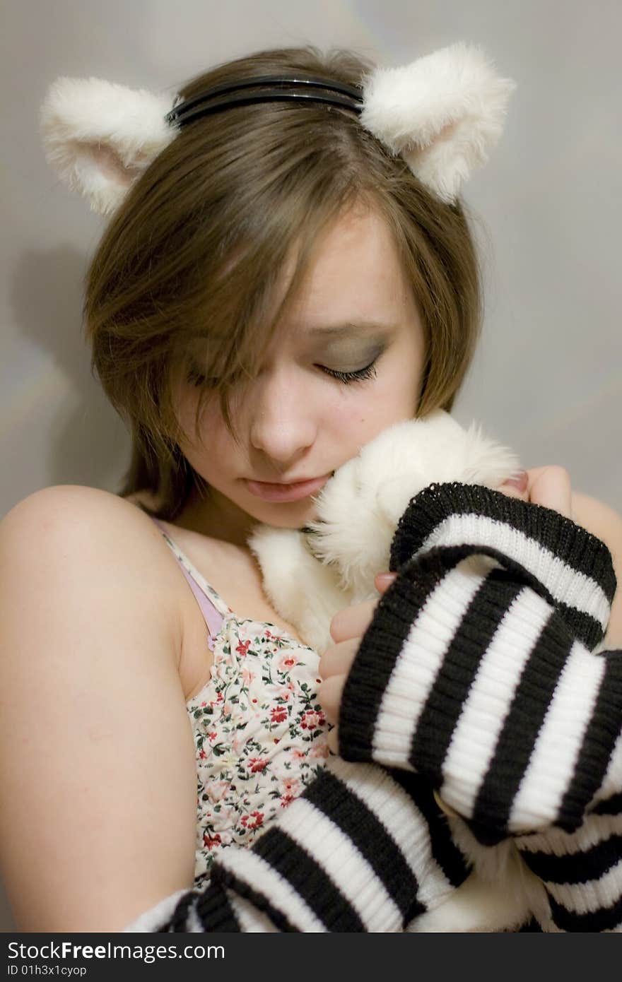 Sweet girl with the ears on your head. Beautiful girl holds a toy - white kitten. Sweet girl with the ears on your head. Beautiful girl holds a toy - white kitten