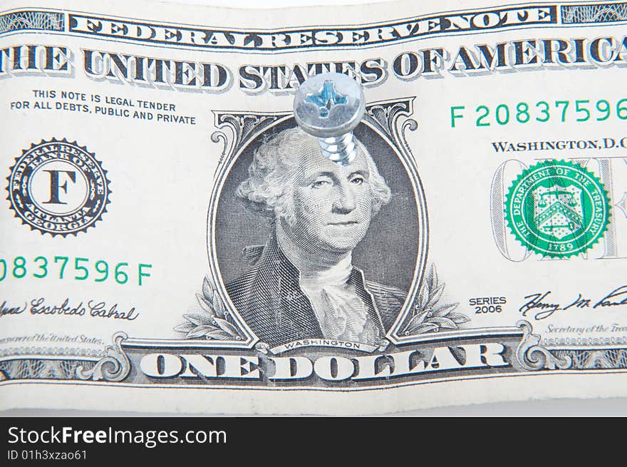 Dollar bill with a screw in the middle of George Washington's head. Dollar bill with a screw in the middle of George Washington's head