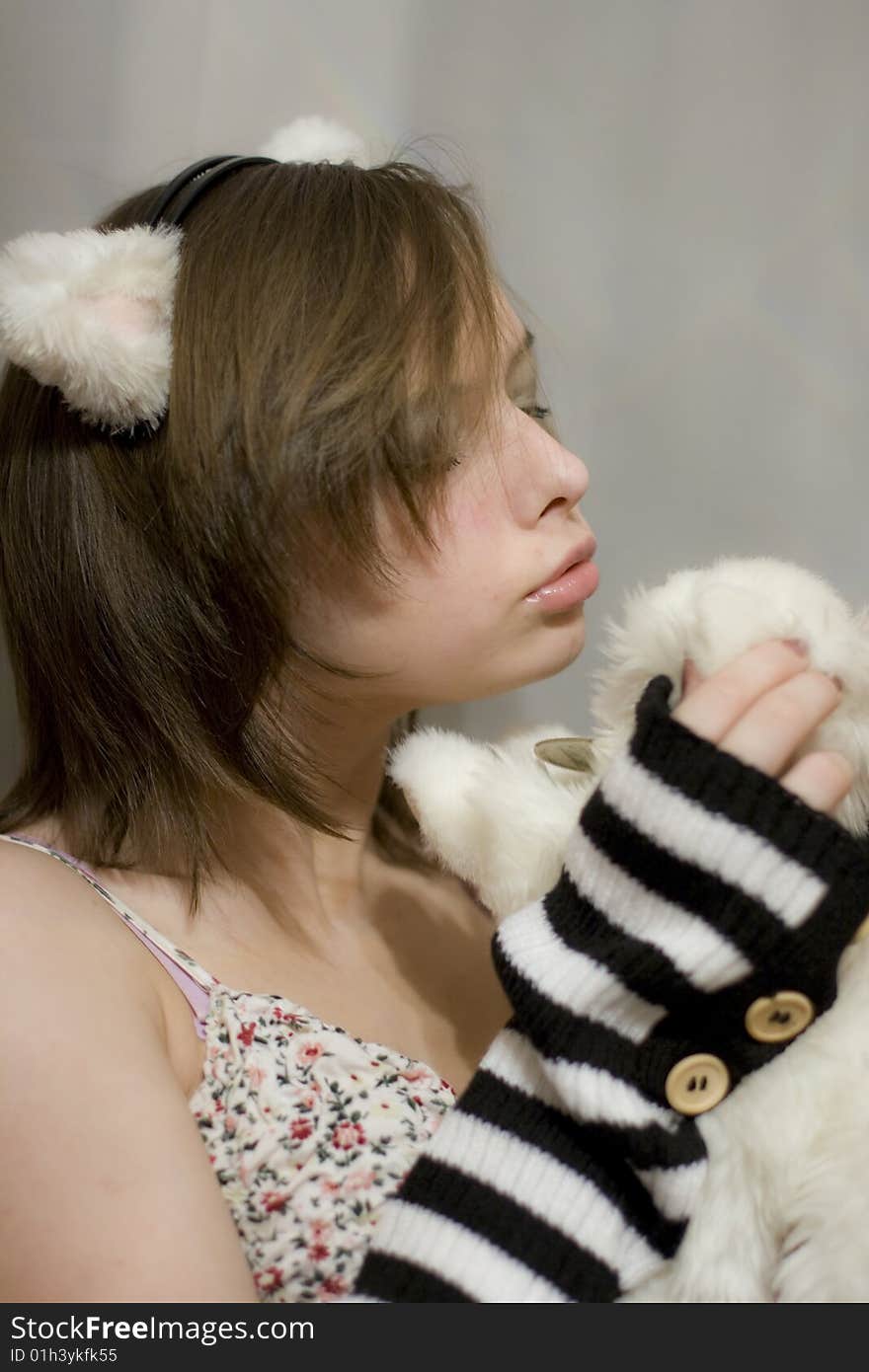 Sweet girl with the ears on your head. Beautiful girl holds a toy - white kitten. Sweet girl with the ears on your head. Beautiful girl holds a toy - white kitten