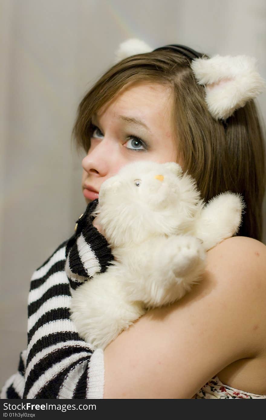 Sweet girl with the ears on your head. Beautiful girl holds a toy - white kitten. Sweet girl with the ears on your head. Beautiful girl holds a toy - white kitten