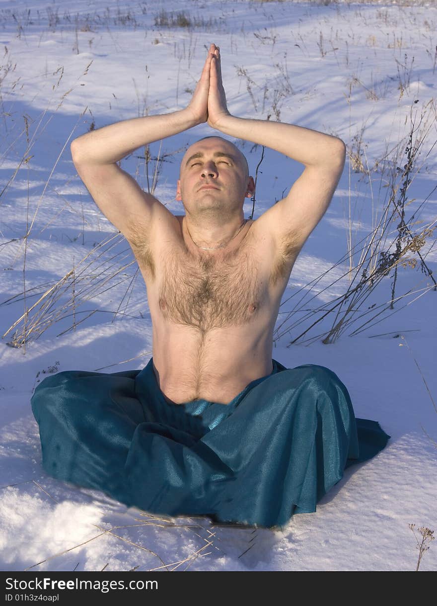 Man doing yoga over snow in winter