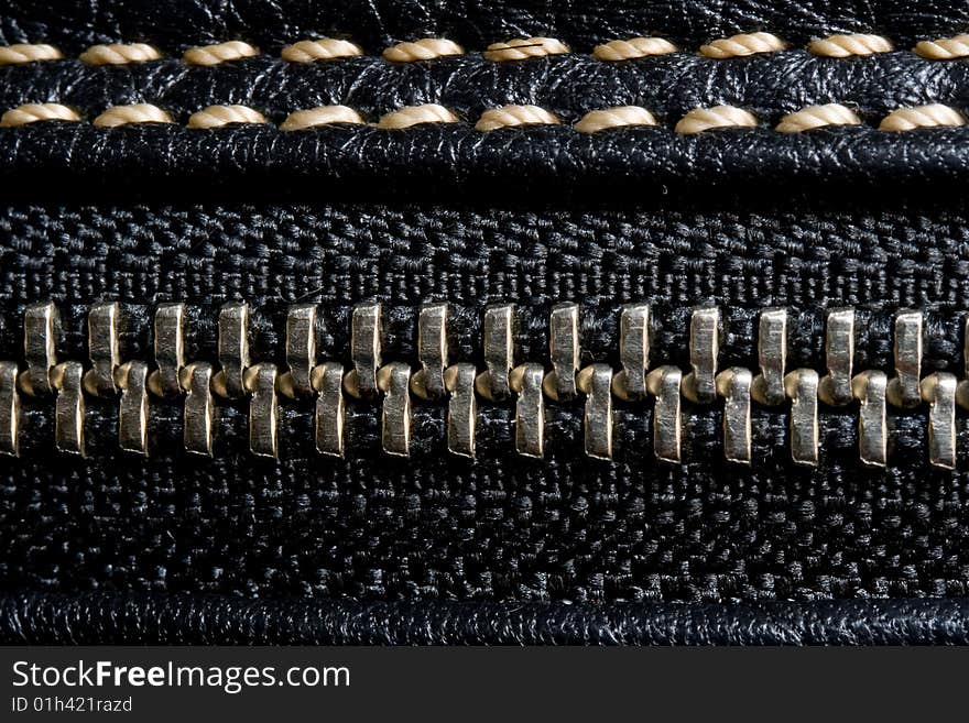 Zipper and black leather macro texture with light thread