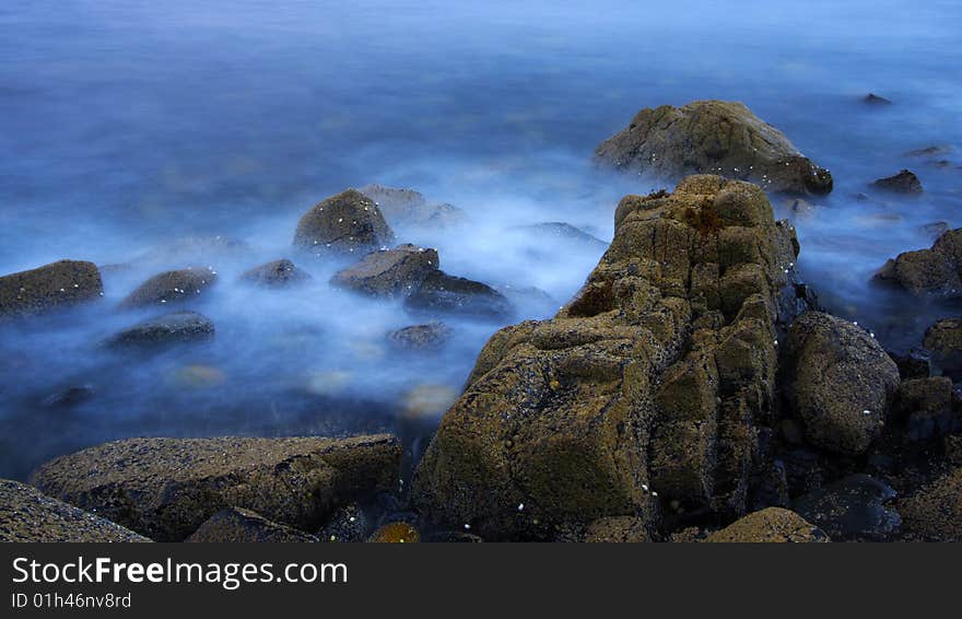 Rocks and sea by a rainy and windy day at Elgol port in scotland, isle of skye. Long exposure.